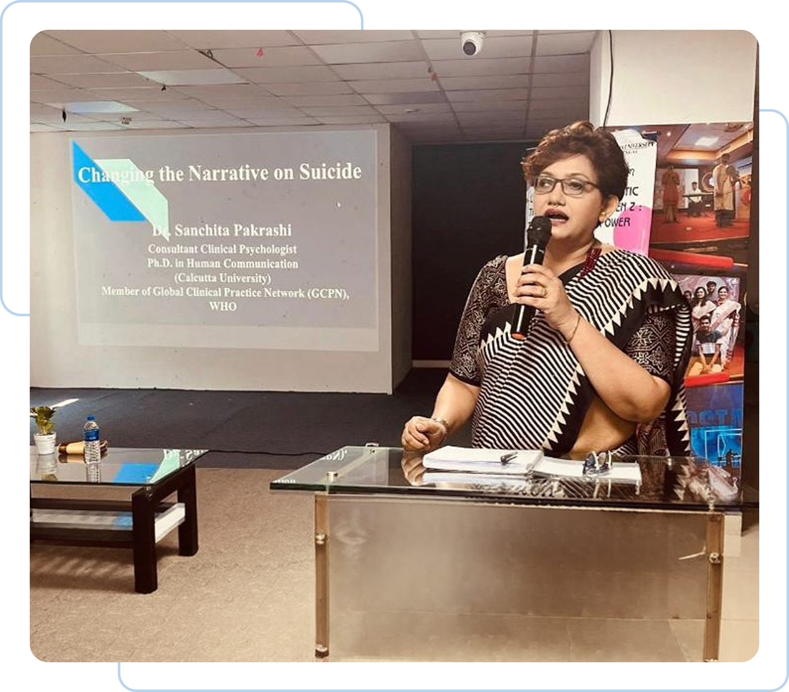 Dr. Sanchita Pakrashi speaking at a podium with a presentation on changing the narrative on suicide.